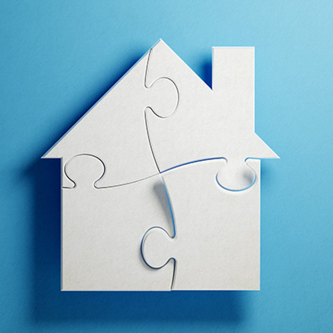 White jigsaw puzzle pieces are forming a house shape on blue background. Horizontal composition with copy space. Clipping path is included.